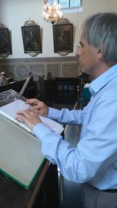 Mann an einem Pult, der einen Text in Blindenschrift vorliest