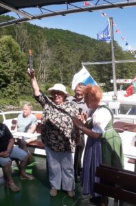 Gerlinde Gregori und Eva-Maria Müller sind zu sehen. Sie stehen nebeneinander, beide leicht zur Seite gedreht. Gerlinde hält den Staffelstab in Händen und hat den rechten Arm in die Luft gestreckt.