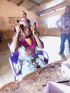 Eine Frau probiert eine Brille auf. Vor ihr auf dem Tisch liegen weitere Brillengestelle